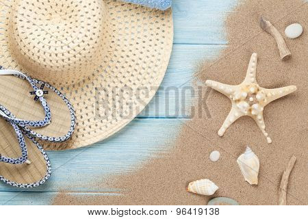 Travel and vacation items on wooden table with sea sand. Top view