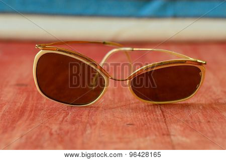 Retro sunglasses on brown wooden background. Vintage theme.