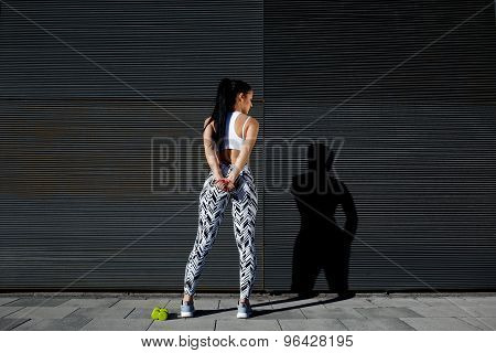 Rear view sporty woman with perfect figure and buttocks taking break against wall with copy space