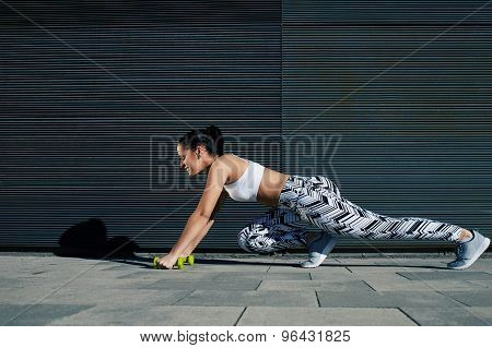 Young fit female in workout gear doing push-ups on black background with copy space outdoors