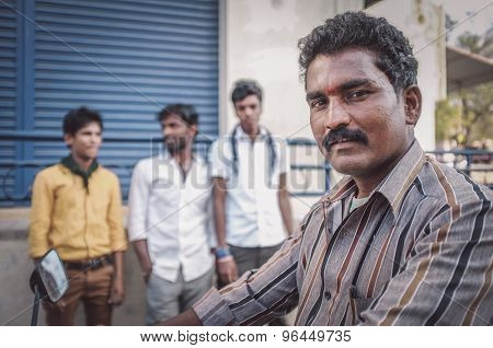 KAMALAPURAM, INDIA - 02 FABRUARY 2015: Indian man on motorbike next to three young men on market close to Hampi. Post-processed with grain, texture and colour effect.