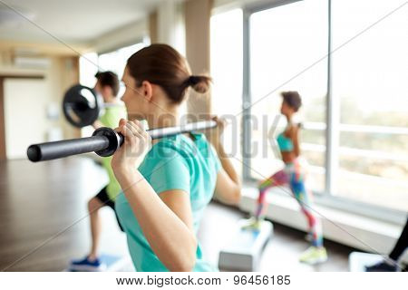 fitness, sport, people and lifestyle concept - close up of sportsmen exercising with bars and step platforms in gym
