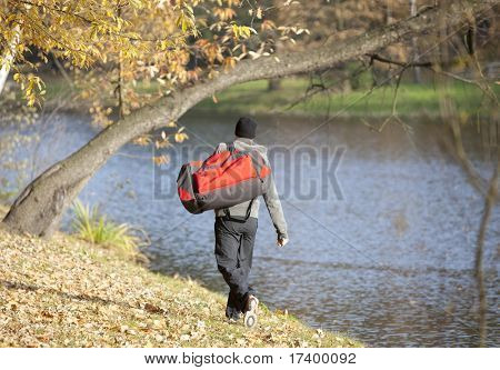 Uomo con la borsa grande sport andando per formazione outdoor nel parco - vista posteriore