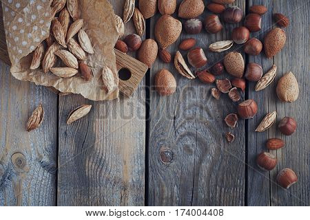 Variety of nuts: almonds mountain almonds and hazelnuts on rustic wooden background. Nuts background with copy space. Top view.