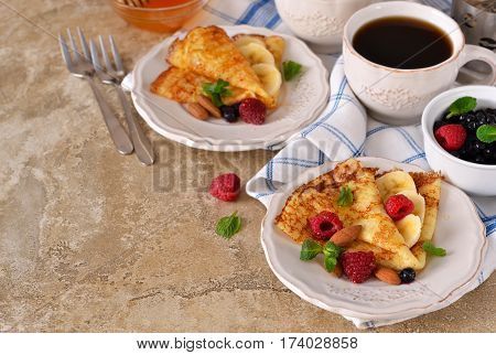 Homemade crepes with maple syrup and berries on a concrete background.