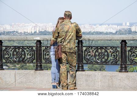 KIEV UKRAINE - AUGUST 8 2015: Ukrainian soldier on leave from the Eastern Ukraine conflict observing Kiev panorama with his girlfriend