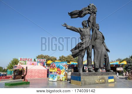 KIEV UKRAINE - AUGUST 8 2015: Soviet Monument dedicated to Russian-Ukrainian friendship under the People's Friendship Arch. Modern amusement park can be seen right behind