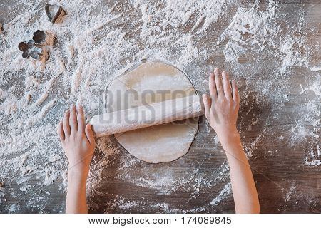 'Partial top view of child kneading dough for cookies