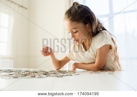 side view of concentrated little girl playing with puzzles at home
