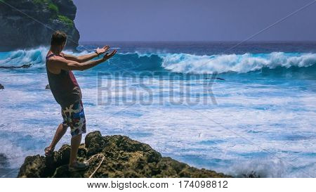 Man Provoke Ocean Waves on Tembeling Coastline at Nusa Penida island, Bali , Indonesia