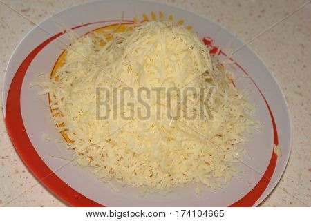 heap of grated cheese. Pile of cheese shavings on plate