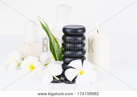 Spa with hot stones, herbal compress balls, candle and flowers on white background