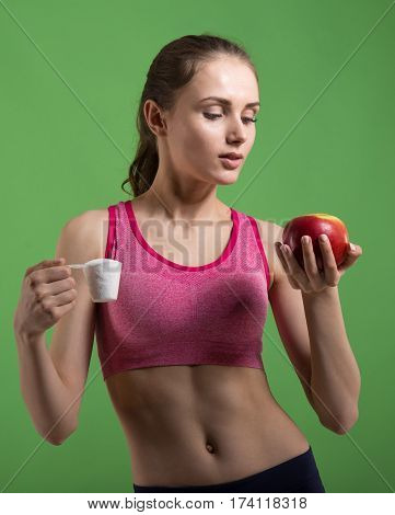 Caucasian girl that chooses to eat sports nutrition or apple. Choice concept.