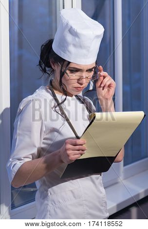 Female doctor in surgery reading patient notes
