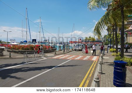 PORT LOUIS, MAURITIUS - NOVEMBER 29, 2012: Unidentified people walk by the street in Caudan waterfront area of Port Louis, Mauritius.