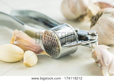 Garlic and garlic press on kitchen table.