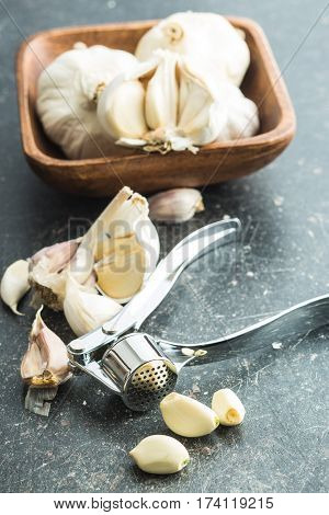 Garlic and garlic press on kitchen table.