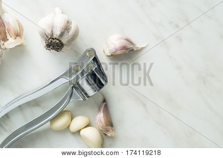Garlic and garlic press on kitchen table. Top view.