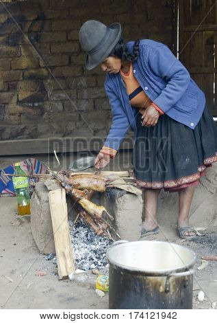Native Peruvian woman preparing guinea pigs over fire. Guinea pigs are special dish in Peru prepared for weddings and religious ceremonies. October 22 2012