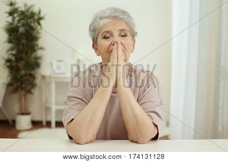Praying elderly woman at home