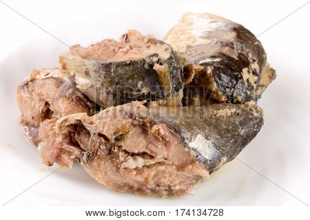 Canned pilchard fish on a plate isolated on white background.