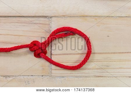 bowline knot made from red synthetic rope tightening on wooden background.