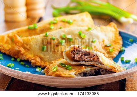 Chebureki on a plate. National Ukrainian Russian Turkish Romanian and Tatar food. Meat pastry meal on a table. Close-up shot.