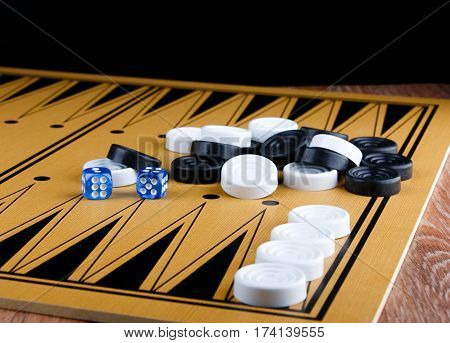 pile of checkers and blue dices on backgammon board