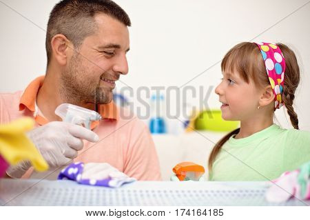 happy father with his small daughter cleaning table together at home