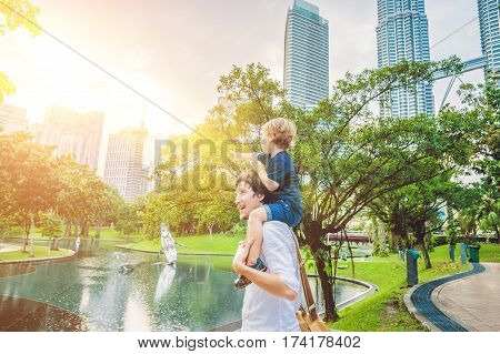 Father And Son Travelers In Malaysia Against A Background Towers Patronas Twins. Traveling With Chil