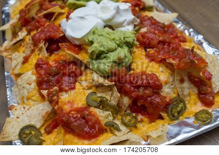 Mexican guacamole nachos with sour cream and salsa