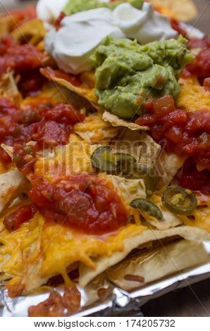 Mexican guacamole nachos with sour cream and salsa
