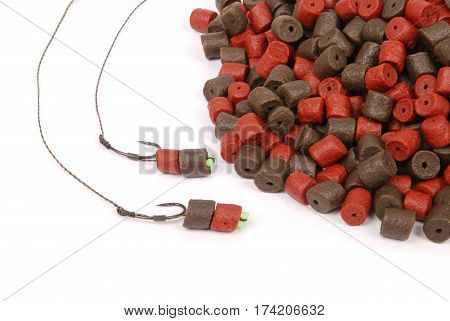 Fishing bait with hook and brown with red pre-drilled halibut pellets for carp fishing isolated on white background with soft shadow
