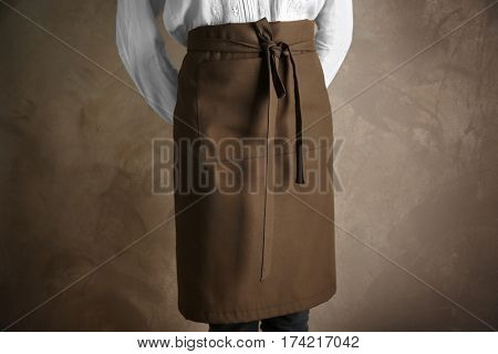 Woman wearing apron on color background