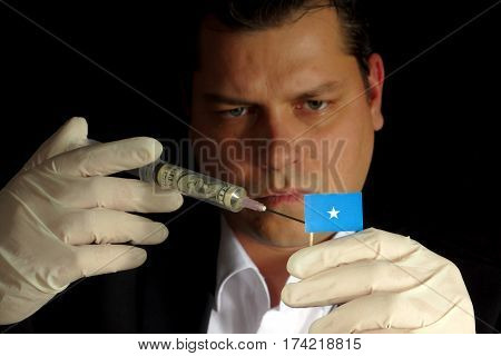 Young Businessman Gives A Financial Injection To Somalian Flag Isolated On Black Background