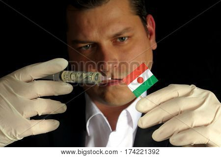Young Businessman Gives A Financial Injection To Nigerien Flag Isolated On Black Background