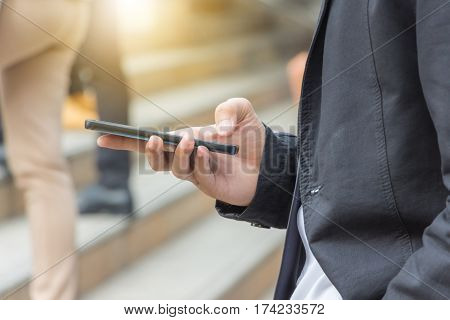 Close up of young business man using mobile smartphone blurry background.