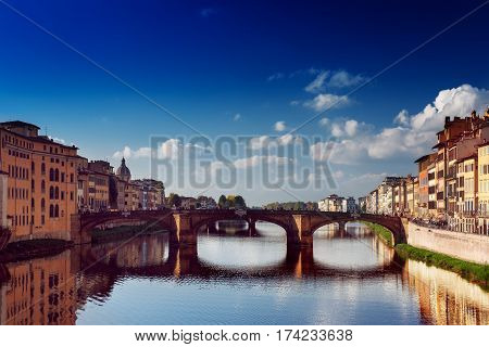View from the river to the famous italian medieval bridge - Ponte Vecchio in Florence with blue sky and clouds, travel outdoor Italy sightseeing background