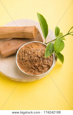 Ayurvedic Chandan powder or sandalwood paste in silver bowl with sticks and leaves placed over sahan or sahana or circular stone base for creating paste