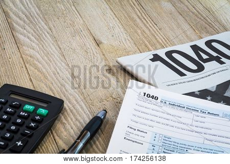 Tax preparation forms with pen and calculator on wooden table for tax year 2016