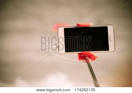 taking picture by smart phone selfie stick on blurred beautiful at beach background Vacation concept
