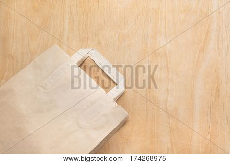 Clean brown kraft paper bag lying on a plywood table.