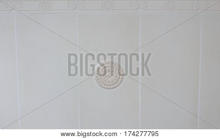 Decor element from plaster on the white tile background in the bathroom