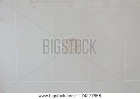 Decor element from plaster on the white tile background in the bathroom