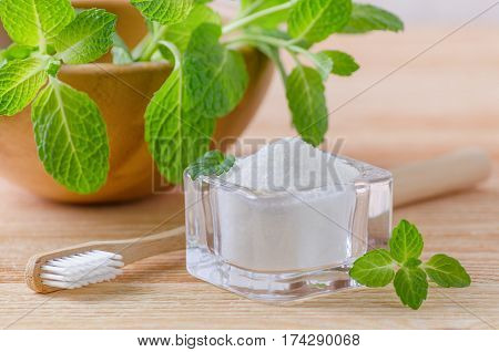 alternative natural toothpaste xylitol soda salt and wood toothbrush mint on wooden background