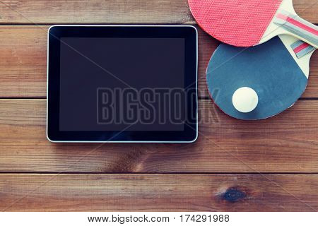 sport, technology, game and objects concept - close up of ping-pong or table tennis rackets with ball and tablet pc computer on wooden floor