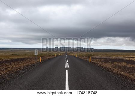 Iceland Road Leading Straight To The Far Away Mountains. Empty Straight Road Line In Rural Icelandic
