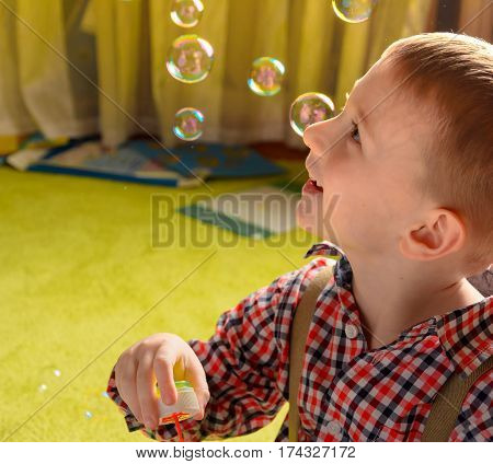 a child inflates soap bubbles and smiling