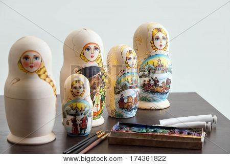 Set of wooden nested dolls - russian matryoshkas on the table at workshop, selective focus, white background