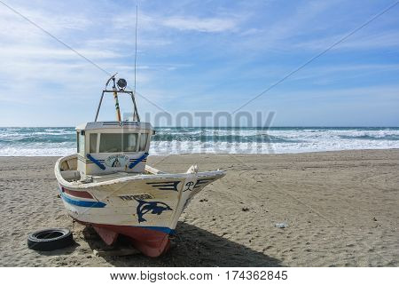 CABO DE GATA SPAIN - FEBRUARY 9 2016: A colored fishing boat at the shore of national park Cabo de Gata near Almeria (Andalusia Spain) and sea waves on the background.